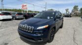 Blue Jeep SUV in the foreground at a car dealership lot, with rows of minivans behind and an EZ Loan Auto Sales sign in the distance.