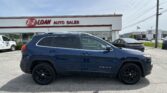 Blue Jeep Cherokee SUV parked in front of the E-Z Loan Auto Sales storefront, other cars and a Toyota dealership visible in the background.