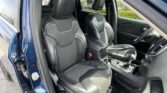 Blue SUV interior with black leather front seats and visible passenger seatbelt, open door on the left side.