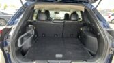 Open SUV cargo area with third-row seats folded, showing black carpet and rear interior.