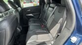 Back seat area of a blue car with black leather seats, headrests, and visible seat belts.