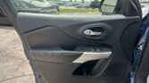 Interior view of a car door panel with window controls and door handle; parking lot visible through the window and side mirror