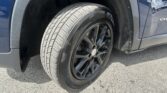 Close-up of a tire and black alloy wheel in the front wheel well of a blue SUV, showing tread pattern and fender edge.