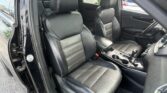 Interior of a black leather SUV showing two front seats, center console, and gear shifter visible through an open door.