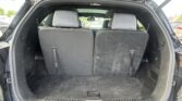 Open hatchback showing empty cargo area with upright rear seats in a black SUV, daylight outside.