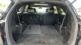 Open tailgate showing the spacious cargo area of a black SUV with the third-row seats upright and headrests visible.