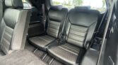 Two black leather rear seats with headrests in a car, viewed from the back seat area through the rear window.