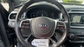 Close-up of a Kia steering wheel and dashboard inside a car, with a dealership lot visible through the windshield.