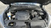 Open-hood engine bay of a Kia SUV showing the engine cover, battery, and front components.