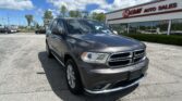 Gray SUV parked in a dealership lot in front of an E-Z LOAN AUTO SALES storefront under a blue sky with clouds.