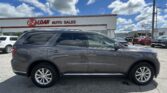 Grey SUV in the foreground outside E-Z Loan Auto Sales on a sunny day.