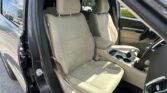 Beige fabric front seats in a vehicle, front door open to show the interior and center console with cupholders