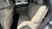 Rear seat area of a beige SUV with three passenger seats and headrests, viewed from the open side door.