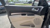Open car door interior with beige panel; view of a parking lot and other vehicles through the window and in the side mirror.