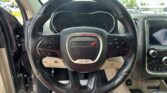Driver's view of a Dodge steering wheel with digital instrument cluster and center console visible.