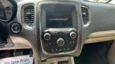 Car dashboard center console with a Dodge infotainment screen displaying the Dodge logo, flanked by air vents and chrome trim.