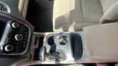 Interior of a car showing the center console with cup holders, gear shift, and beige seats and upholstery.