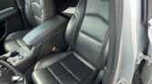 Interior of a car showing black leather front seats, center console, and partial rear seating; door frame and seat belts visible.