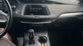 Inside a car looking toward the dashboard and center console, with the gear shifter in view and a parking lot outside the windshield.