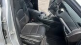 Open car door reveals black leather driver and front passenger seats, center console, and steering wheel in a modern SUV, parked outdoors.