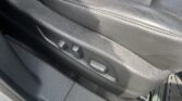 Black leather car seat with visible stitching and side controls/adjustment levers along the seat base.