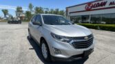 Silver Chevrolet SUV in the foreground at a car lot with an EZ Loan Auto storefront under a clear blue sky, daytime sun.