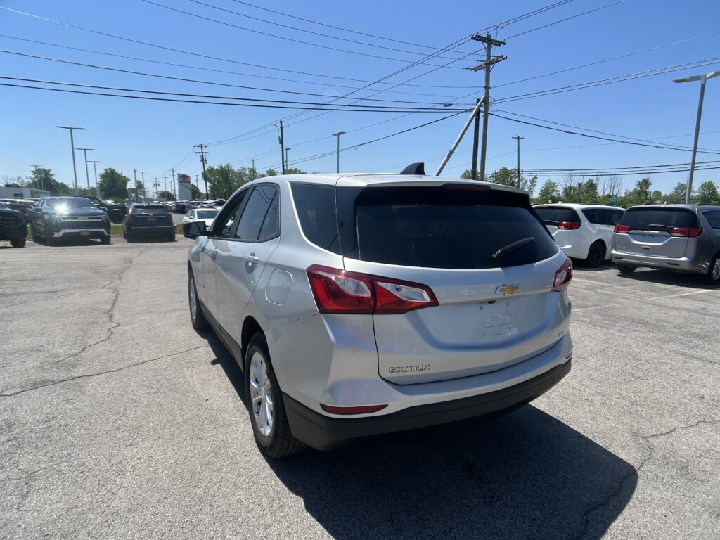 Silver Chevrolet Equinox SUV in a crowded parking lot under a clear blue sky with power lines overhead