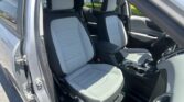 Open car door reveals gray and black front seats with quilted pattern and center console visible inside the vehicle interior.