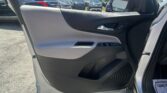 Open car door showing gray interior panel; parking lot with multiple SUVs visible in the background, sunny day.