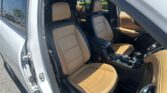Open car door showing tan leather front seats and center console in a modern SUV interior.