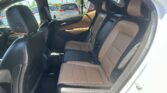 Rear passenger seats in a two-tone brown and black leather car interior, with headrests and seat belts visible