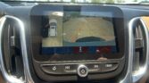 Infotainment screen showing the rear camera view with orange parking guidelines on a parking lot behind the car.