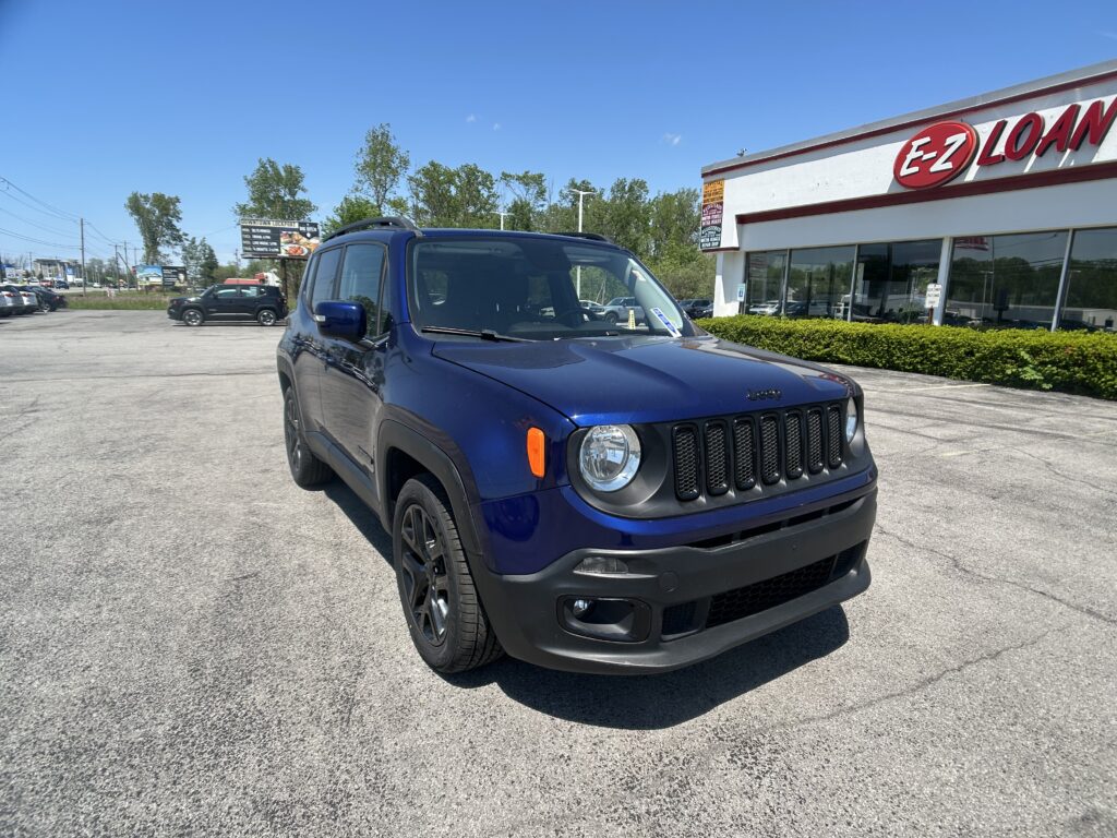 Blue Jeep SUV parked in a parking lot in front of an E-Z LOAN storefront on a sunny day.