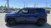 Blue GMC Yukon Denali parked in a dealership lot with white vans and power lines overhead.