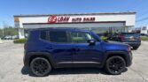 Blue SUV in foreground at EZ Loan Auto Sales dealership with white building and red sign in bright daytime sky.