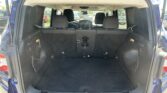 Open rear hatch of a blue SUV showing an empty cargo area with folded rear seats and net pockets on sides in a parking lot.