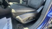 Interior of a blue car showing the front passenger seat, center console, and gear shifter; a paper lies on the floor by the seat.