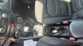 Interior of a car front cabin: center console with climate controls, gear shifter, and a small white paper on the floor mat.