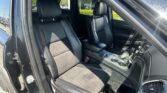 Interior of a dark leather SUV with front seats and center console visible, driver door open to the outside light.