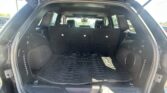Open cargo area of a black Jeep SUV with folded rear seats and a textured cargo mat; the tailgate is raised.