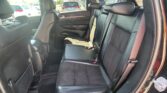 Rear passenger area of a car with black leather seats, three-seat row and headrests, view from the side door.