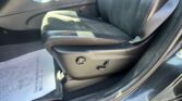 Front passenger seat area of a dark car, showing the center console, seat belt, and a paper mat on the floor.