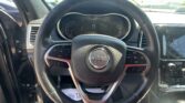Close-up of a Jeep steering wheel with the dashboard behind it and a touchscreen on the right side in a car interior