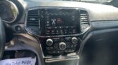 Interior view of a car dashboard with a large touchscreen display showing radio options and climate controls; a flyer on the passenger side reads 'We Take Pride In Your Vehicle'