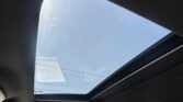 Inside a car, a large panoramic sunroof shows a clear blue sky above the interior.