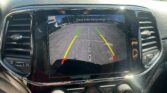Rear/backup camera display on car dashboard showing guiding lines (green, yellow, red) for parking, with 'Check Entire Surroundings' message at top.
