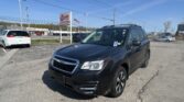 Dark blue SUV in a dealership lot with an EZ Loan Auto Sales sign and a waving American flag in the background