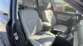 Interior of a car with gray cloth front seats, center console, and steering wheel; driver’s door open.
