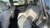 Rear seating area of a gray cloth SUV with three seats and headrests, viewed from the open door; parking lot outside through the windows.