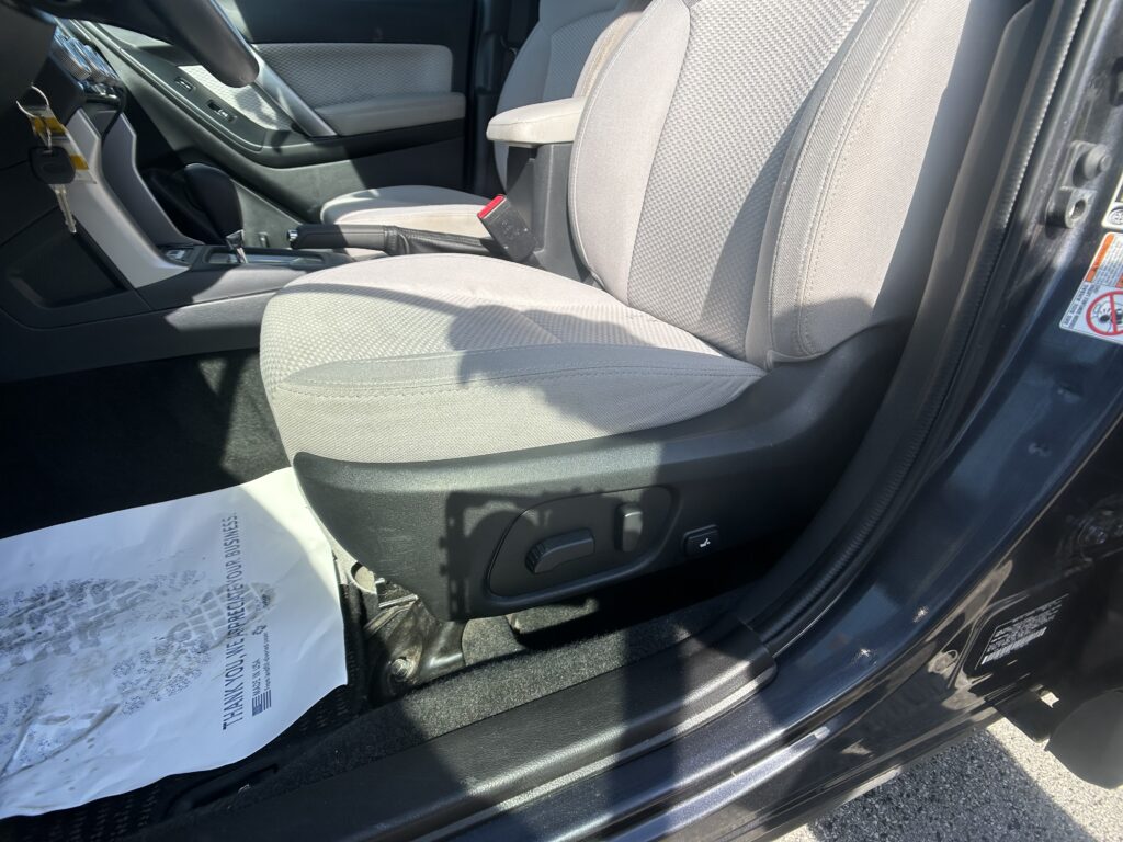 Driver-side interior of a car with gray fabric seats, center console, handbrake, and keys hanging near the door.